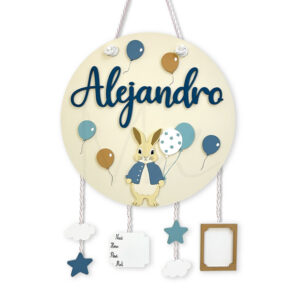 Round beige nursery name plaque reading 'Alejandro' with a bunny and hanging blue balloons, stars, clouds and tags as decorative charms for a baby's room.