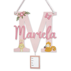 Decorative pink monogram wall plaque: large letter M with a script name 'Marla', floral accents, animal illustrations, and a hanging frame.