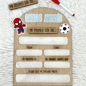 Wooden milestone board for a child named Carlos Andres with prompts 'Mi último día de...' and 'Mi primer día de...,' and blank fields for date, age, teacher, and interests in Spanish.