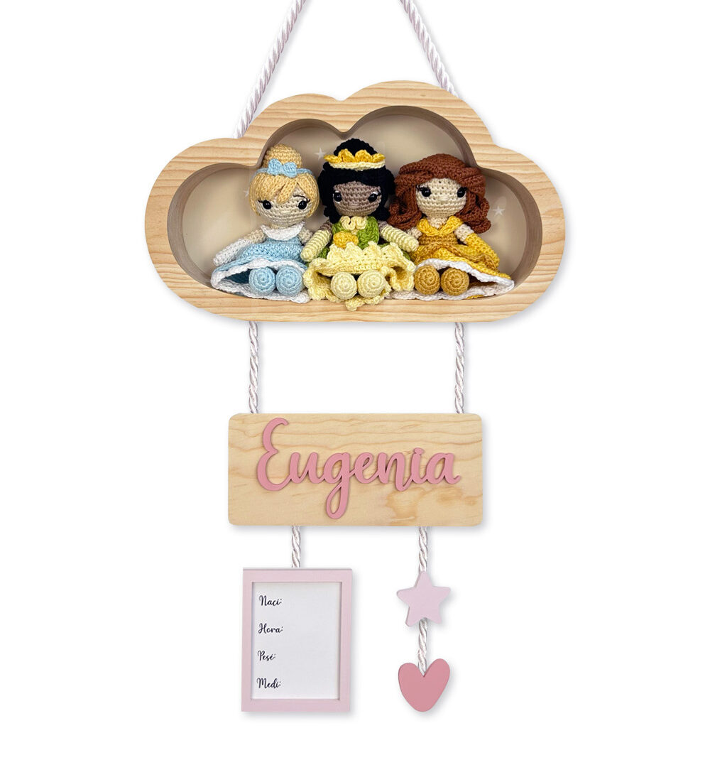 Wooden cloud wall hanging with three crocheted princess dolls and a pink name plaque reading 'Eugenia' for a nursery decor sign.